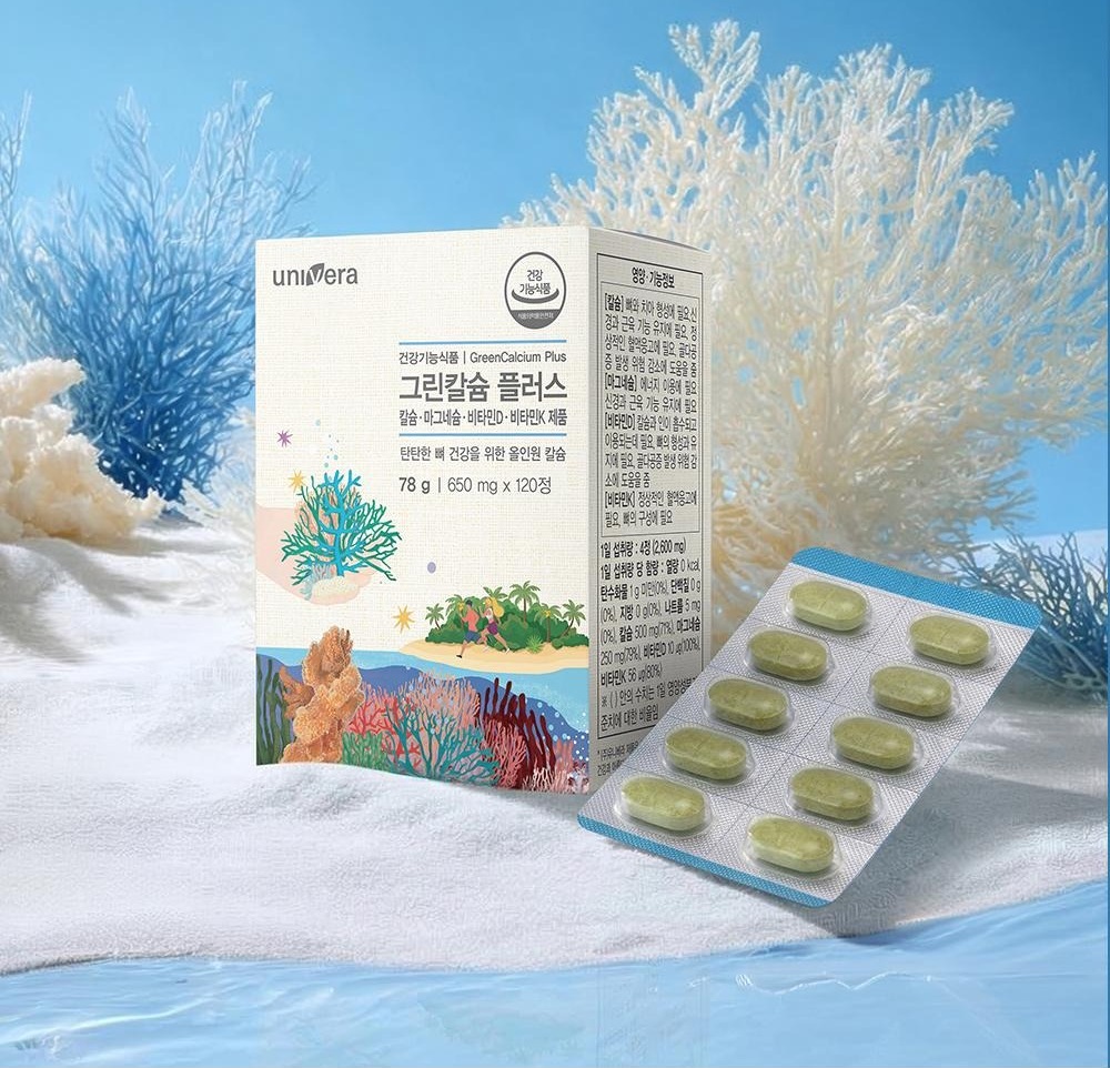 하늘 아래 흰 산호와 모래 위의 그린칼슘 플러스 상자(건강기능식품 | GreenCalcium Plus · 칼슘·마그네슘·비타민D·비타민K 제품 · 78 g | 650 mg x 120정)와 초록 정제 블리스터