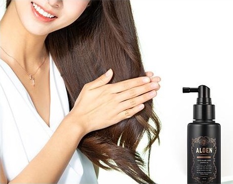흰 셔츠를 입고 긴 머리를 손으로 쓸어내리며 웃는 여성과 오른쪽 아래의 알로엔 안티 헤어로스 앰플