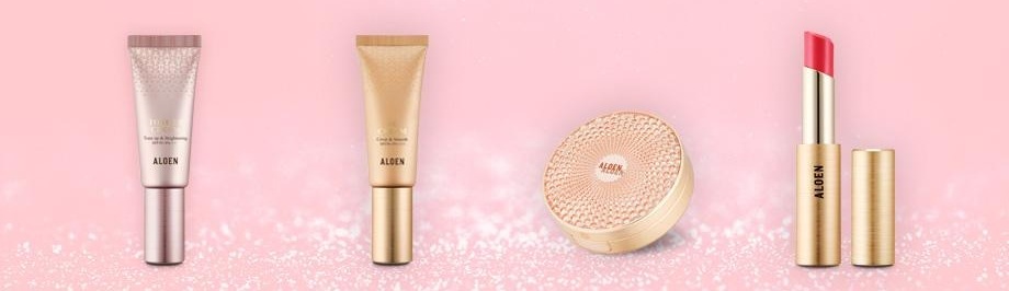 분홍 반짝이 지면 위의 알로엔 메이크업 4종 — 톤업크림(분홍 튜브), 비비크림(금색 튜브), 스킨커버(금빛 쿠션), 립세럼스틱(분홍 립스틱과 금색 뚜껑)