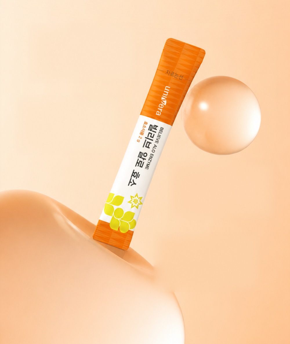 살구색 둥근 면 위에 비스듬히 선 빌리브 알로 효소 스틱과 투명한 구슬
