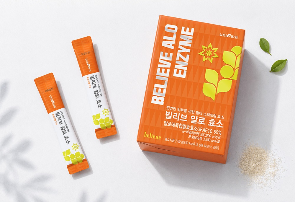 흰 종이 위에 놓인 빌리브 알로 효소 스틱 둘과 30포 상자, 초록 잎 둘과 가루